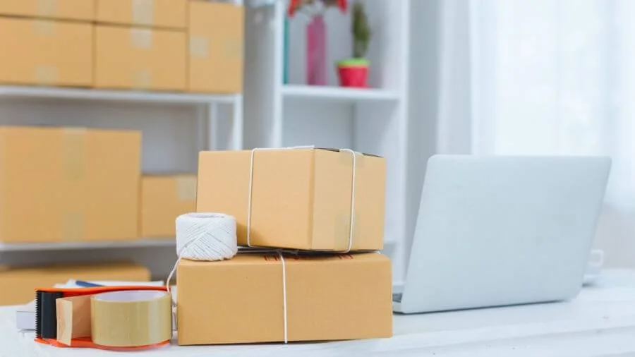 Organized work area with packing supplies, labeled boxes, and shelving for an efficient business workspace.