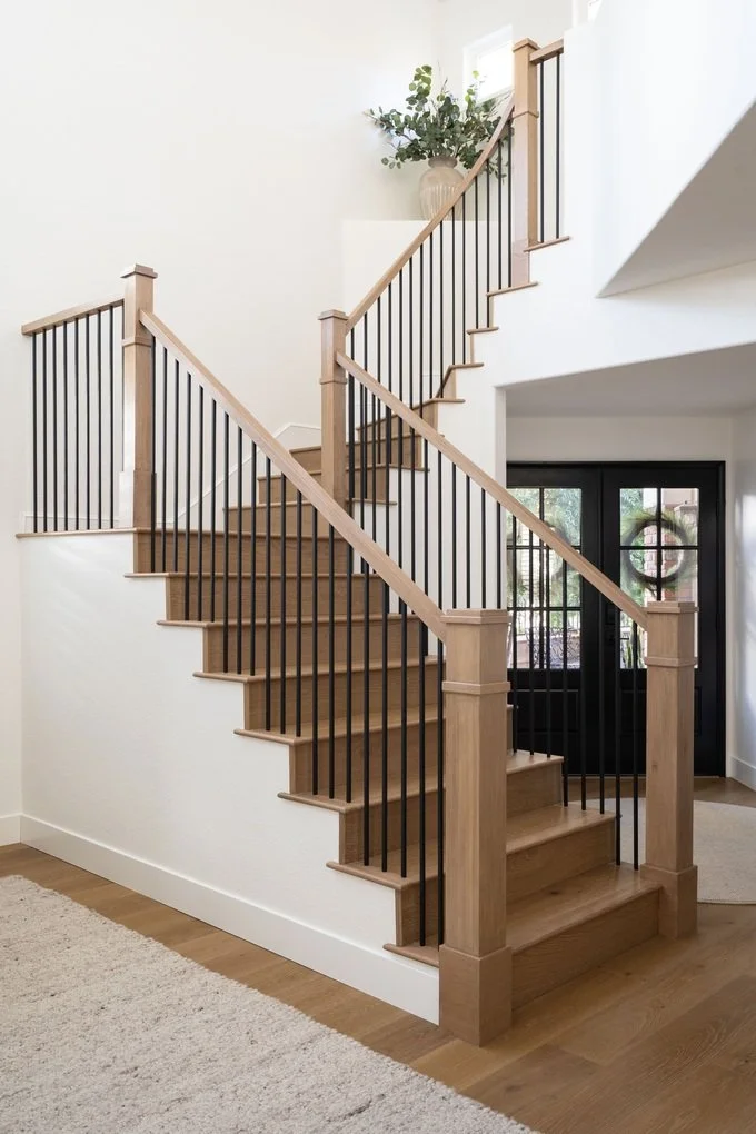 Reimagined interior staircase with warm wood treads, white risers, and a tailored dark railing in a refined French Country home.