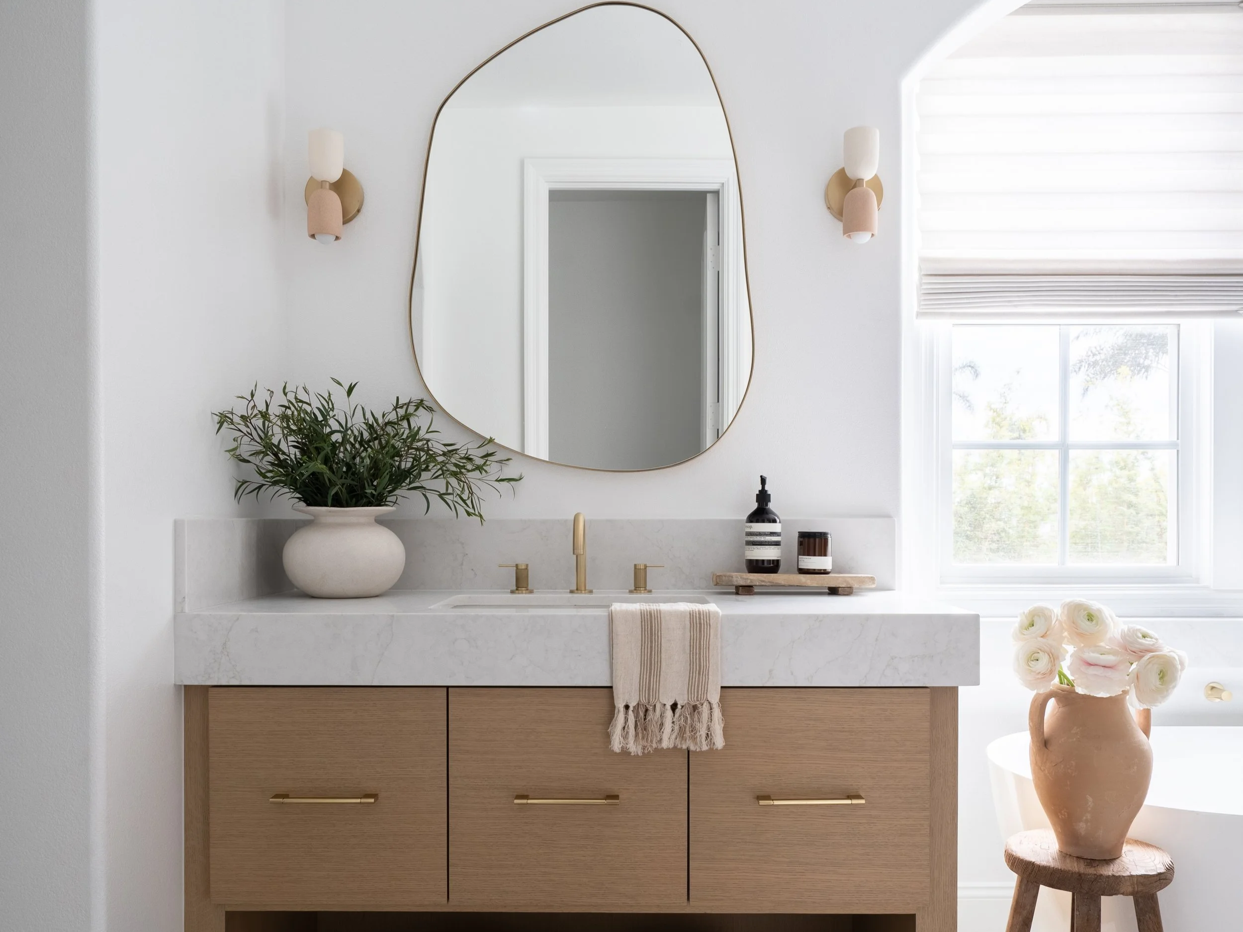Organic modern bathroom renovation in Encintas. Filled with natural liught, a custom slab vanity, architectural lights and a beautiful mirror.