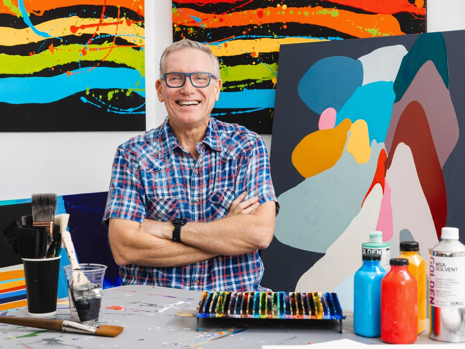 A portrait of an artist for a lifestyle branding photoshoot in his art studio surrounded by his colorful artwork in Austin, TX