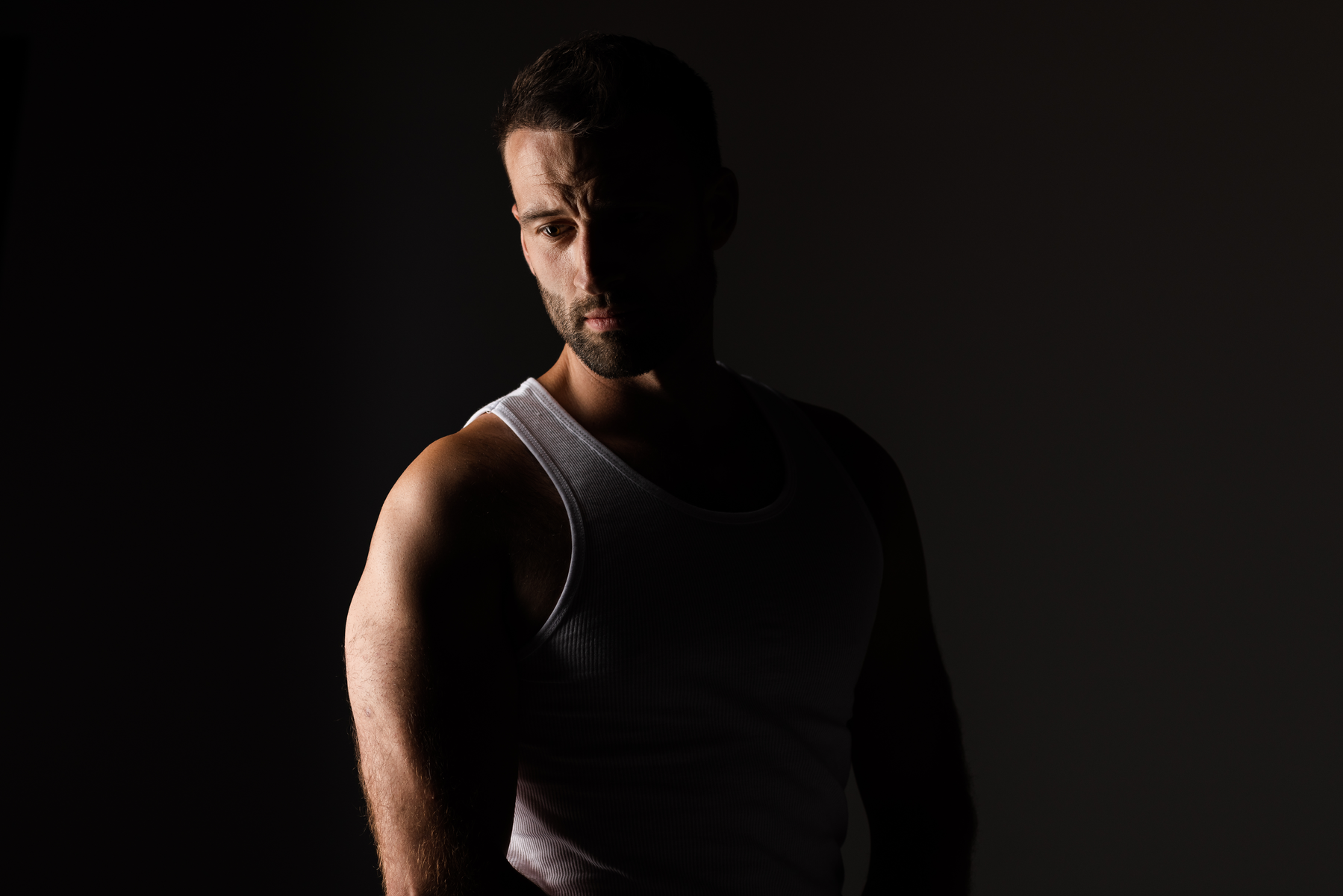 A moody and stylistic portrait of an attractive man looking away from the camera with dramatic rim lighting in Austin, TX