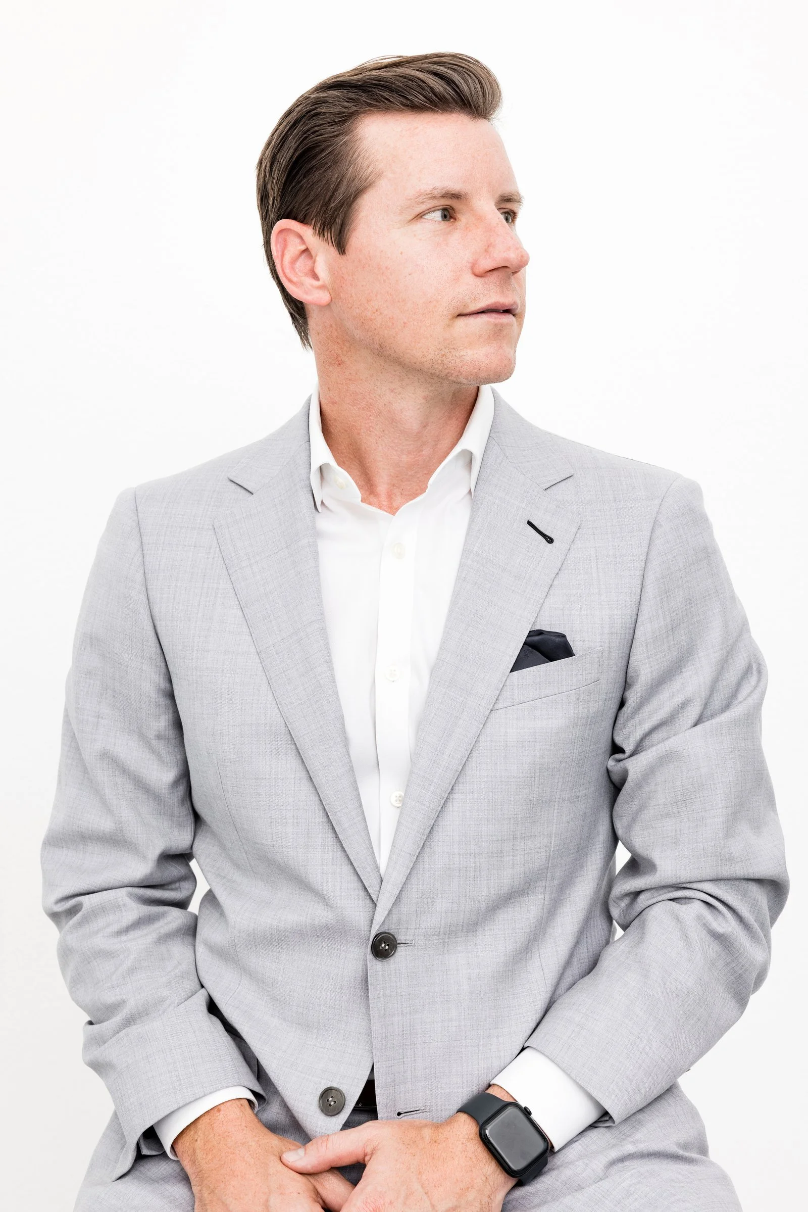 A business corporate professional headshot of a young man in a suit on a white background in Austin, TX