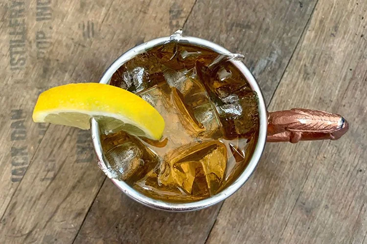 Top-down view of a whiskey drink in a copper mug garnished with a lemon slice.
