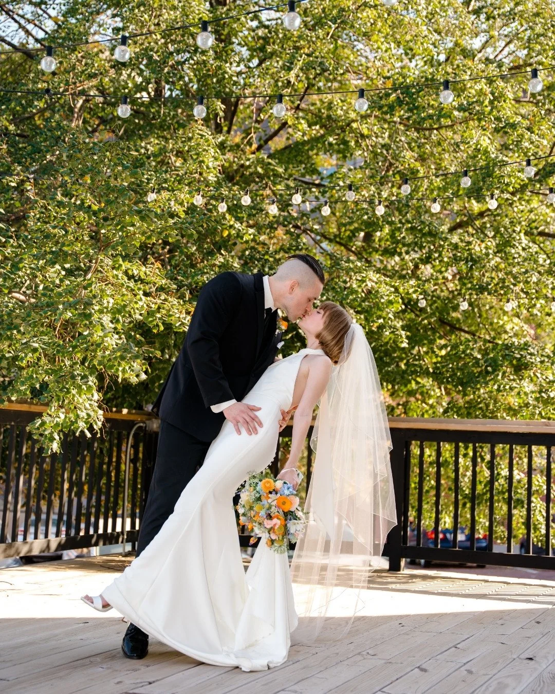 Nighttime view of a brick building with illuminated sign reading '116 Jones Street', surrounding parked cars, and string lights in front.