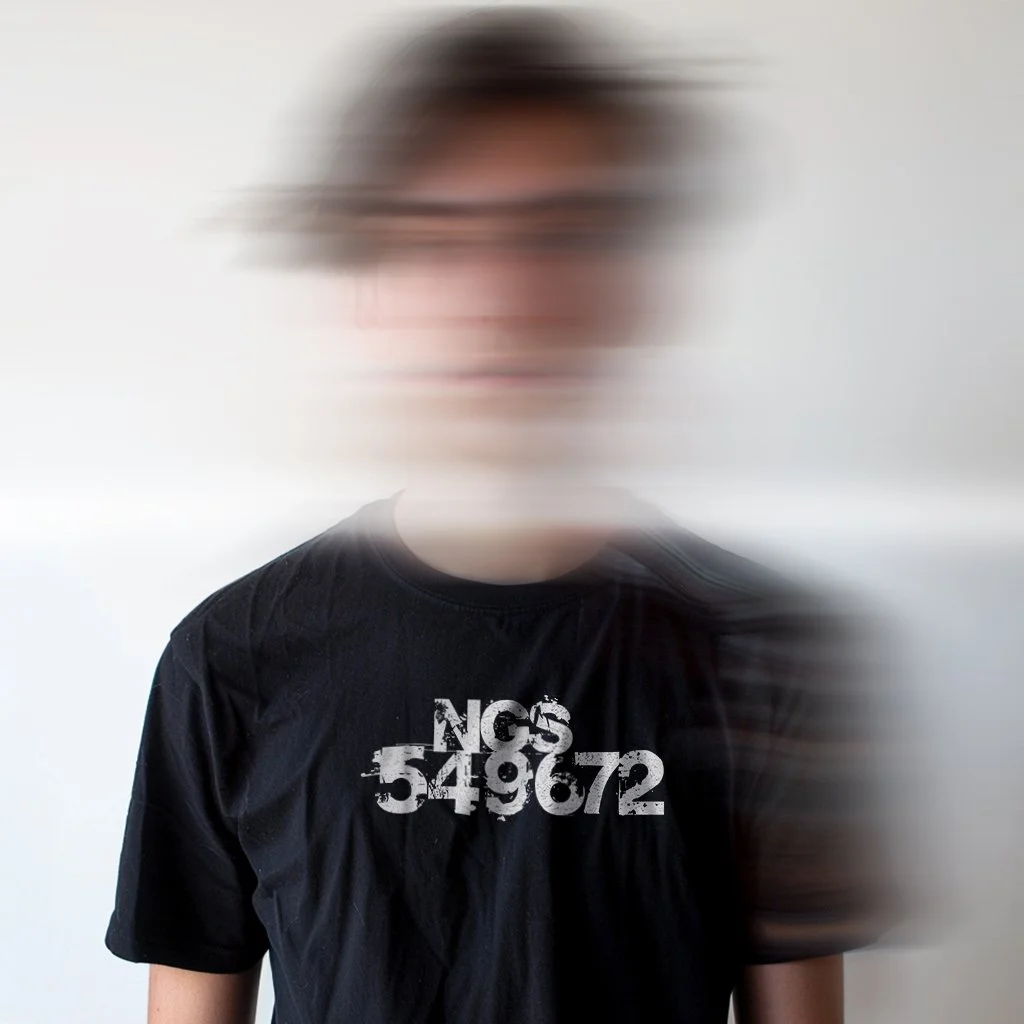 Model with his face blurred wearing a black t-shirt that saysNGS549672