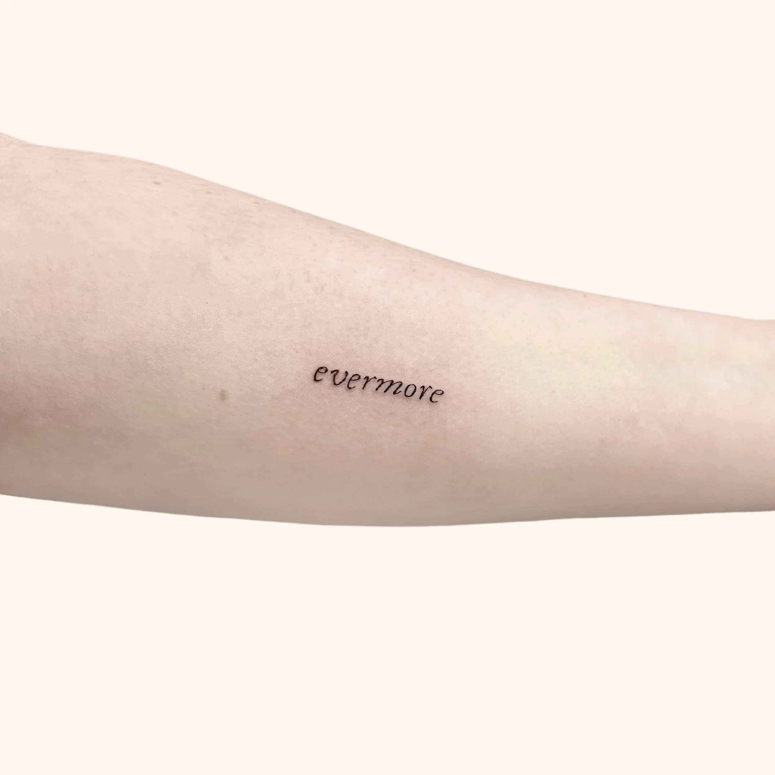 taylor swift italic script tattoo of the word "evermore"