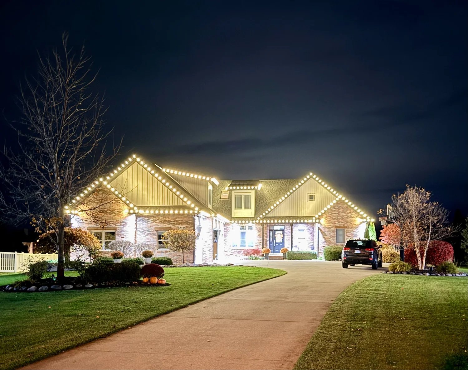 Warm-white holiday roofline lighting on a home at night, installed by Tri-City Lighting