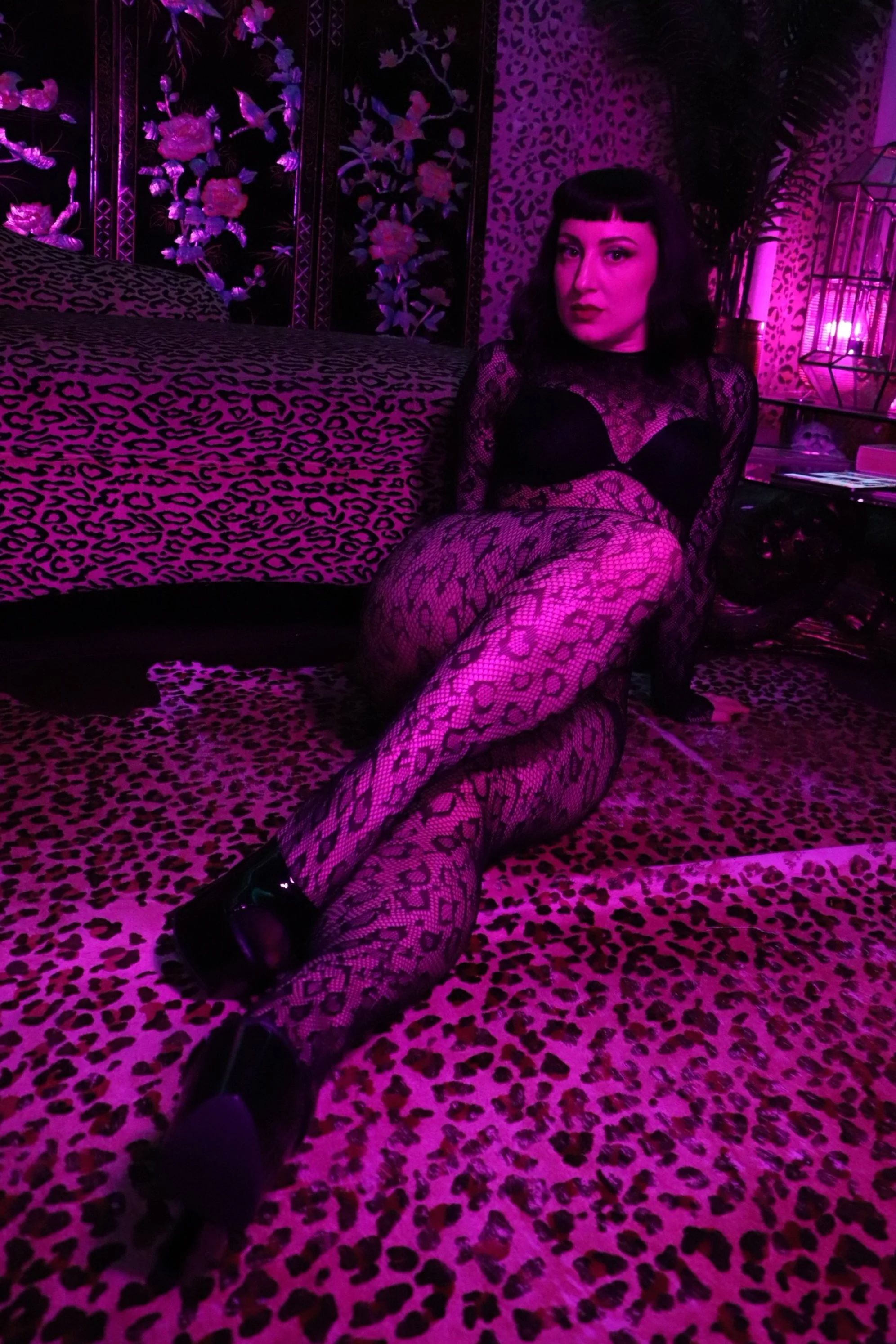 professional dominatrix wearing a leopard bodystocking on leopard carpet