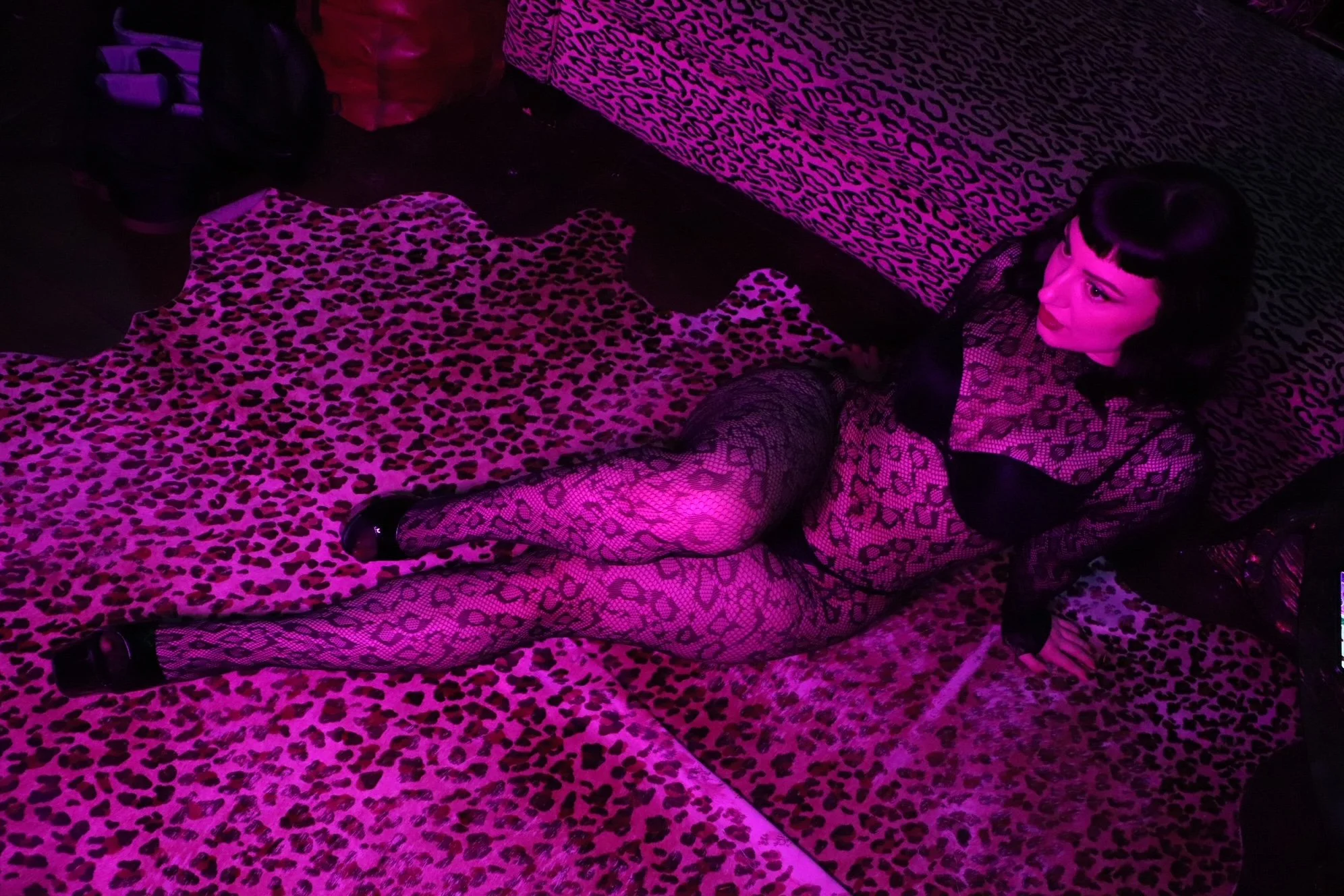 professional dominatrix wearing a leopard bodystocking on leopard carpet