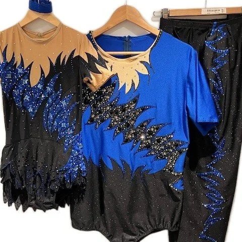 Gekleurde turnkleding met blauwe, zwarte en gouden kleuren en glitters, hangend aan hangers.