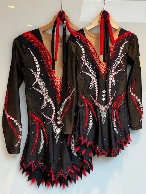 Twee zwarte en rode acrokostuums van Atelier Nadja met glinsterende patronen, versierd met strass steentjes.