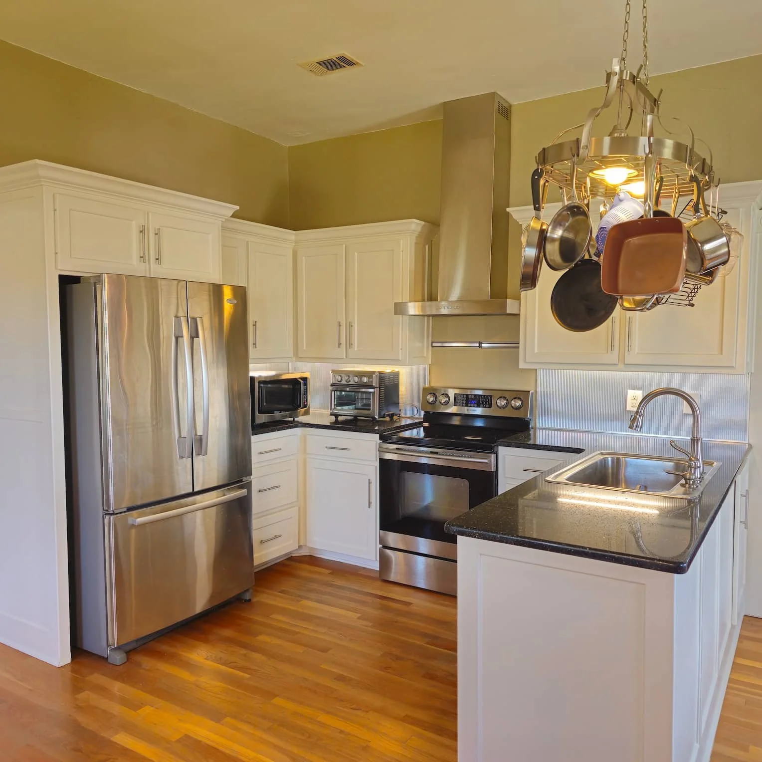 Kitchen with olive-toned walls, white cabinets and trim, and a light-colored ceiling.