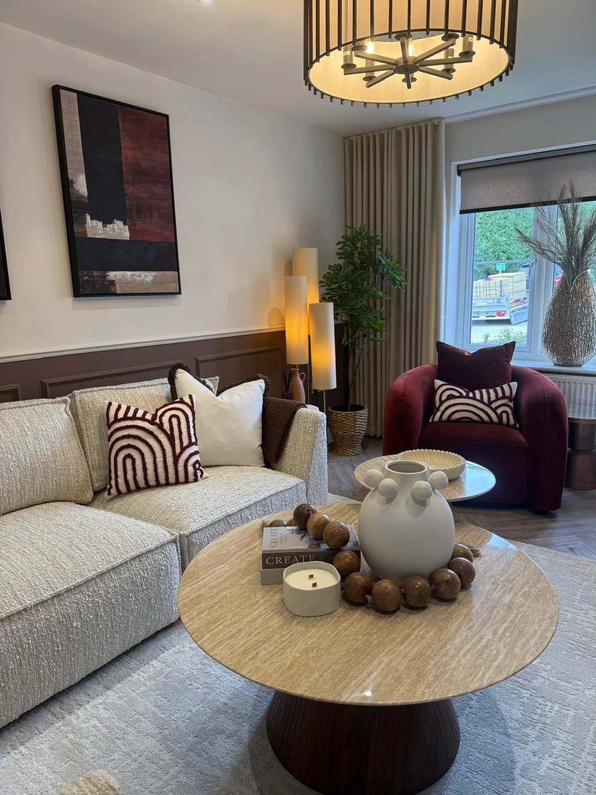 Show home living room interior design featuring cream boucle corner sofa, brown wall panelling and rust velvet armchair
