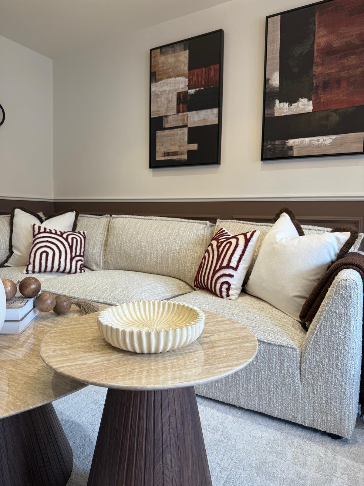 Open-plan dining area with marble-topped table, boucle chairs and walnut media wall at the Hafan y Glyn show home in Colwyn Bay