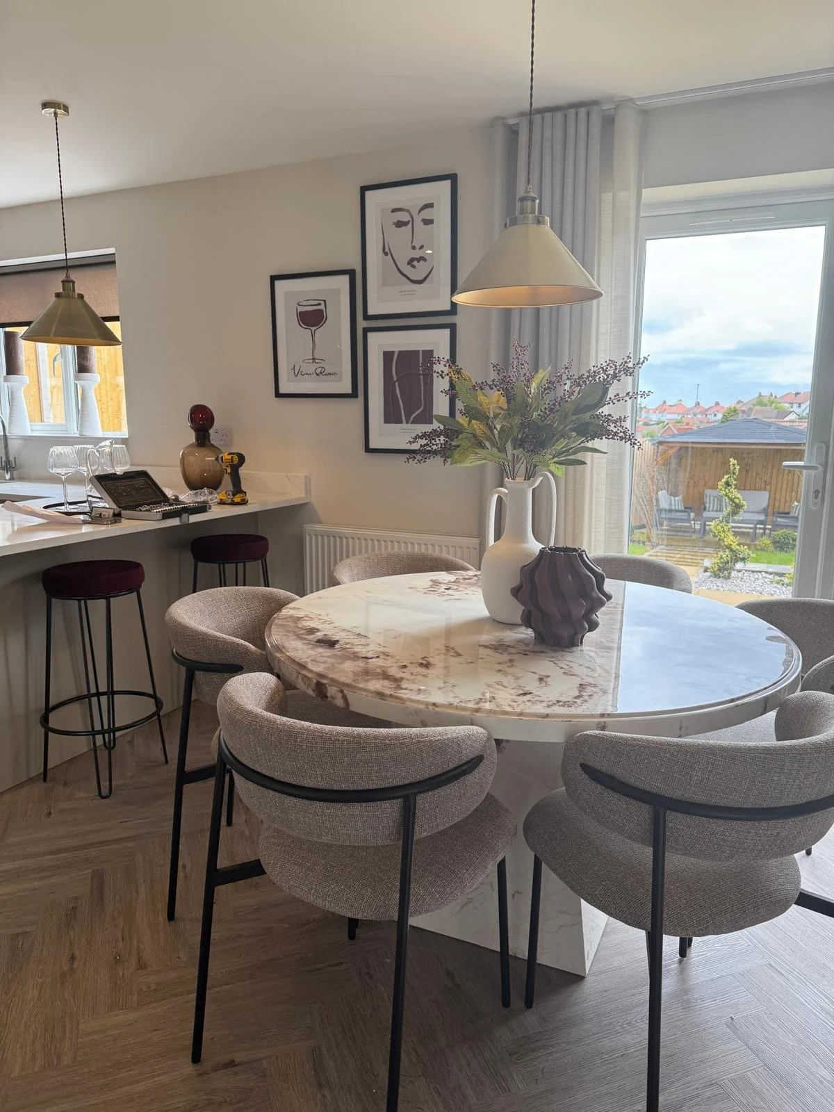 Open-plan dining area with marble-topped table, boucle chairs and walnut media wall at the Hafan y Glyn show home in Colwyn Bay