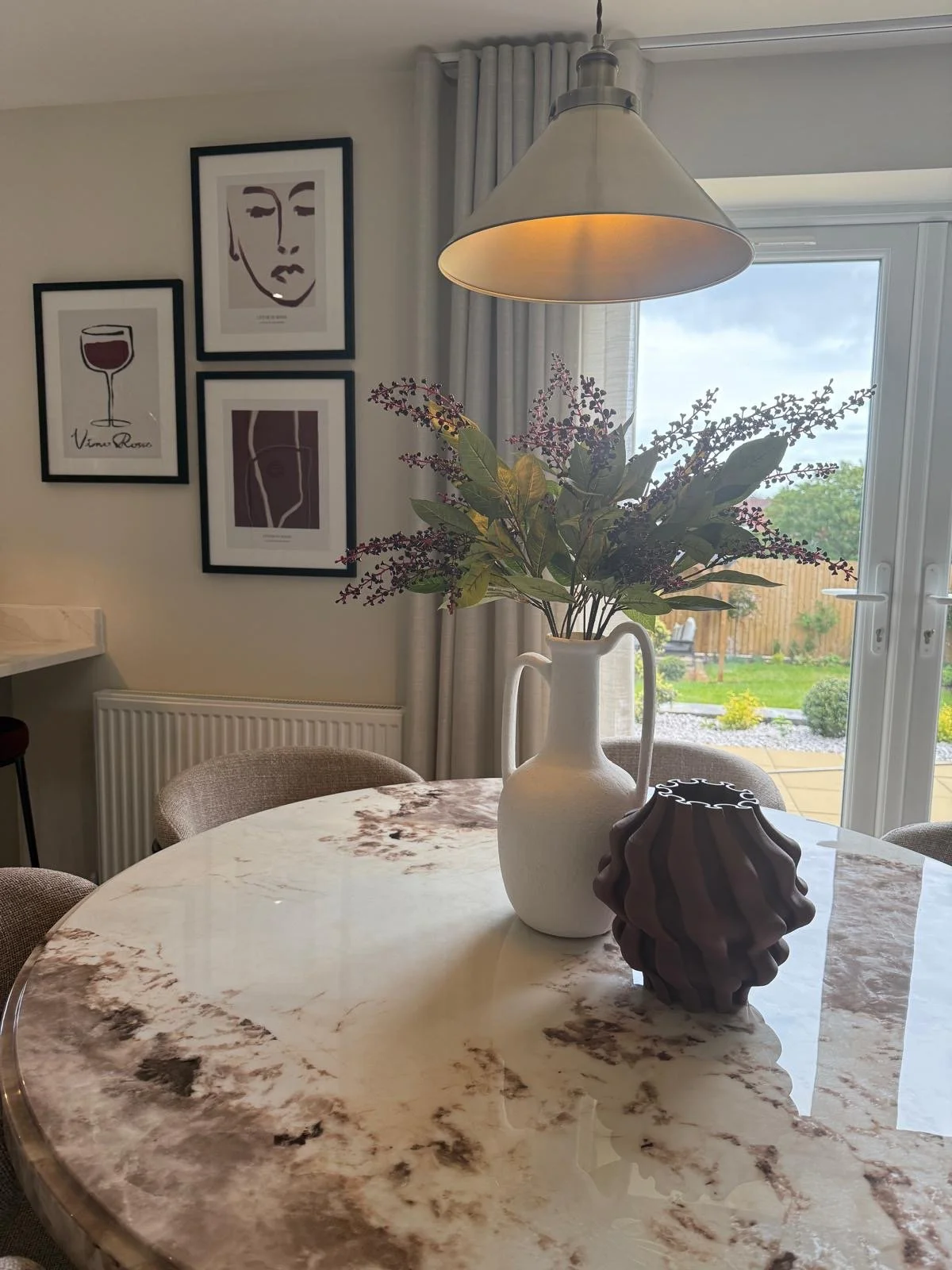 Open-plan dining area with marble-topped table, boucle chairs and walnut media wall at the Hafan y Glyn show home in Colwyn Bay