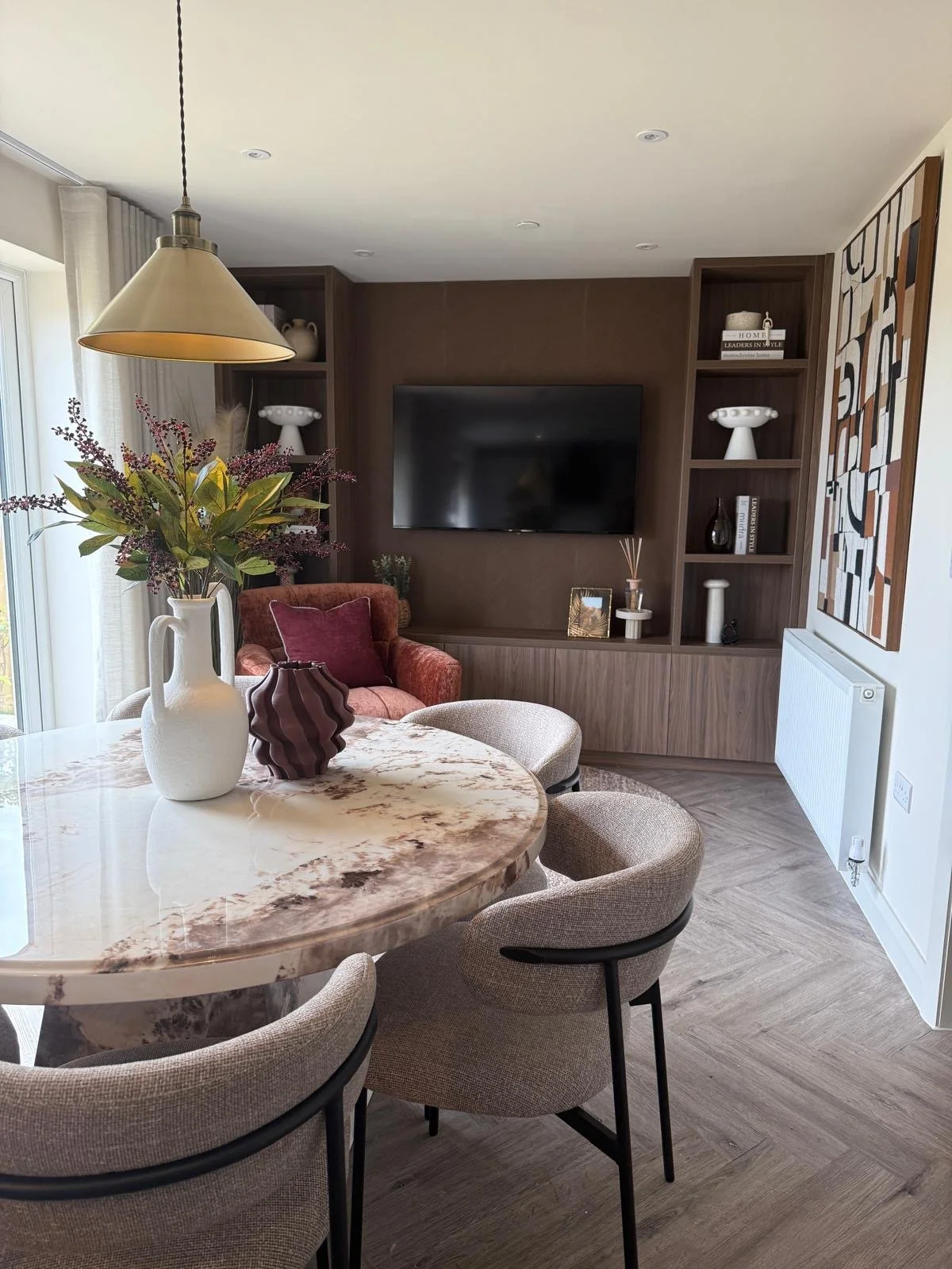 Show home living room interior design featuring cream boucle corner sofa, brown wall panelling and rust velvet armchair