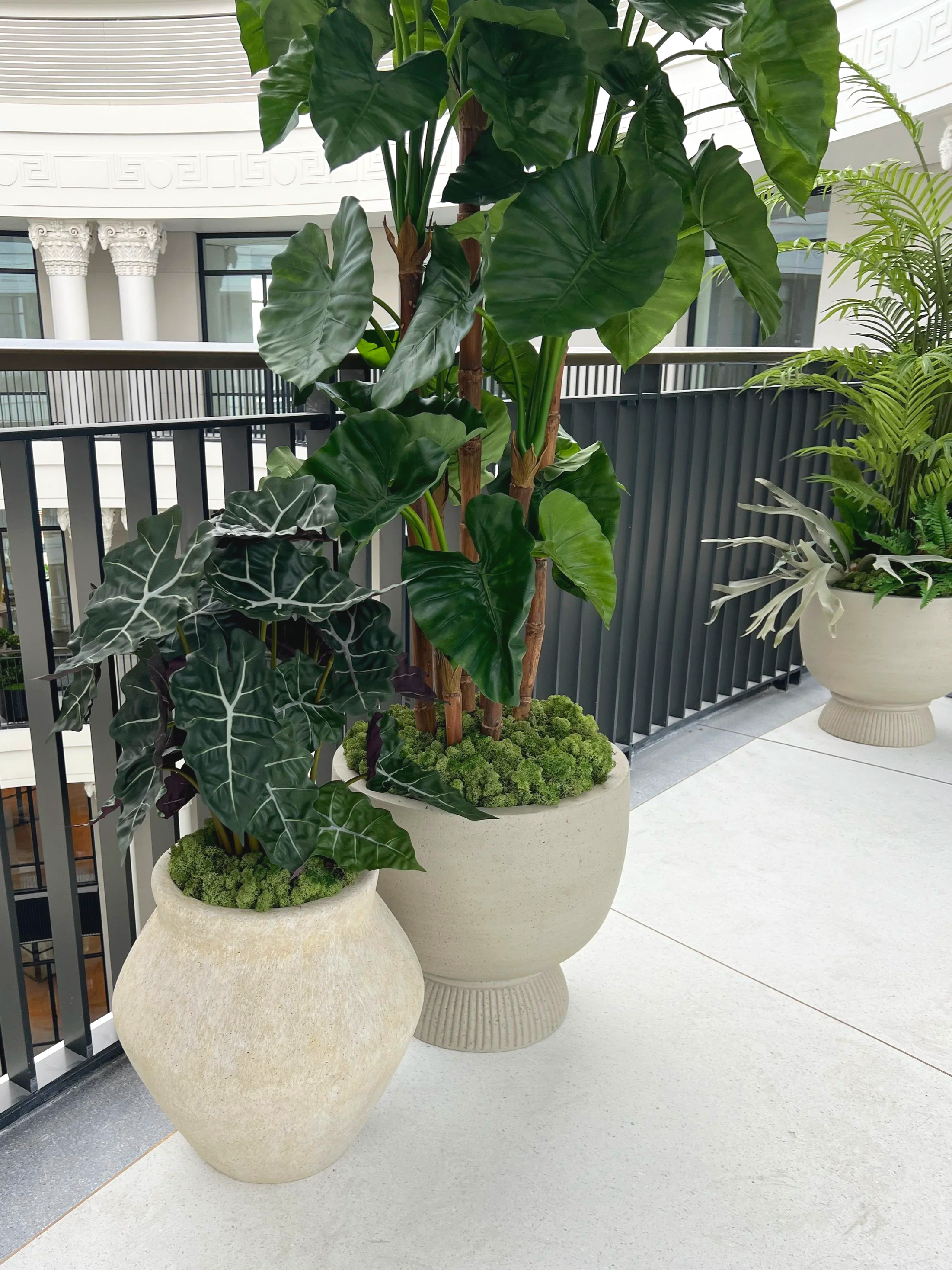 Indoor planted balcony area with replica plant displays.