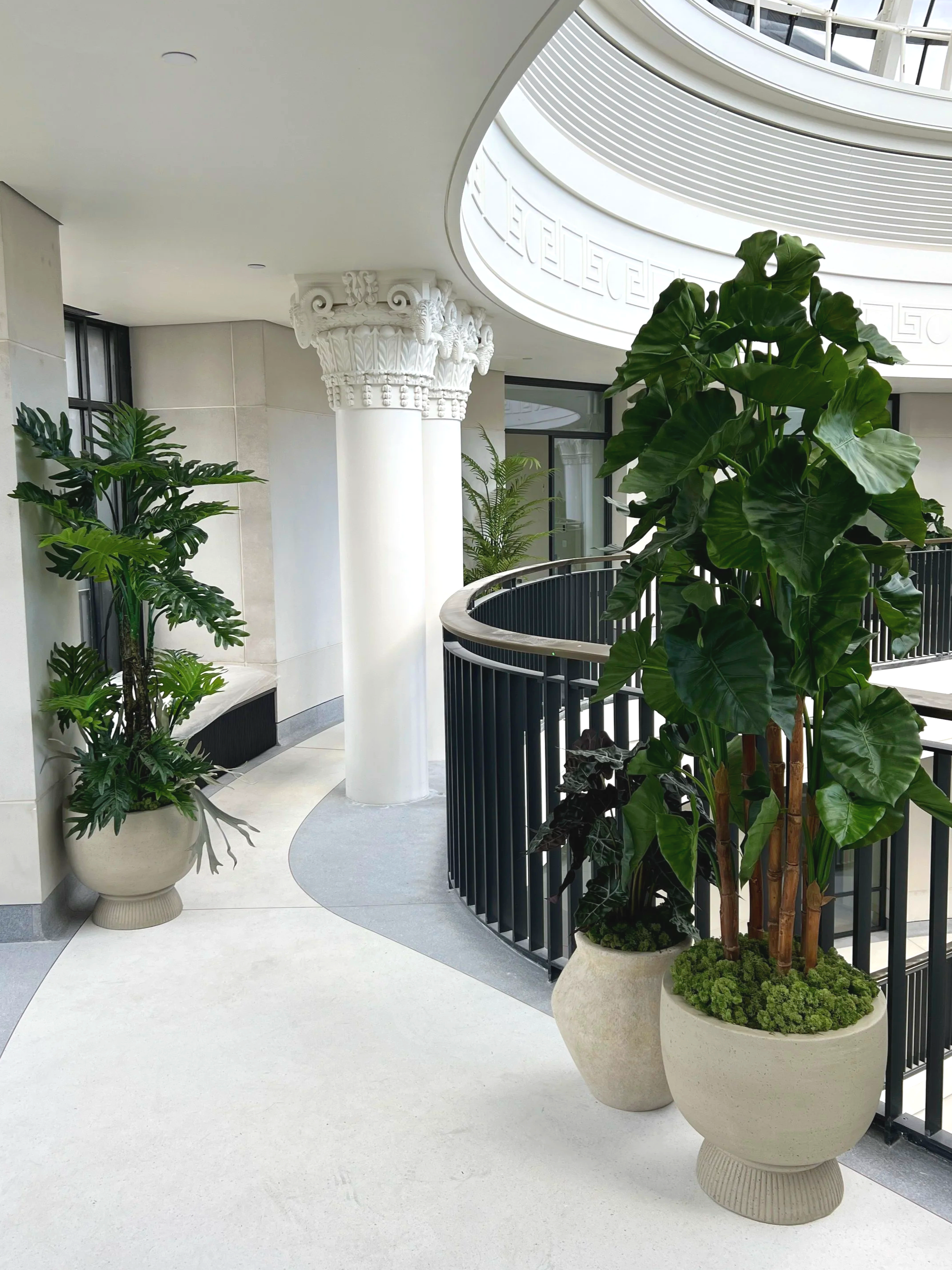 Indoor planted balcony area with replica plant displays.