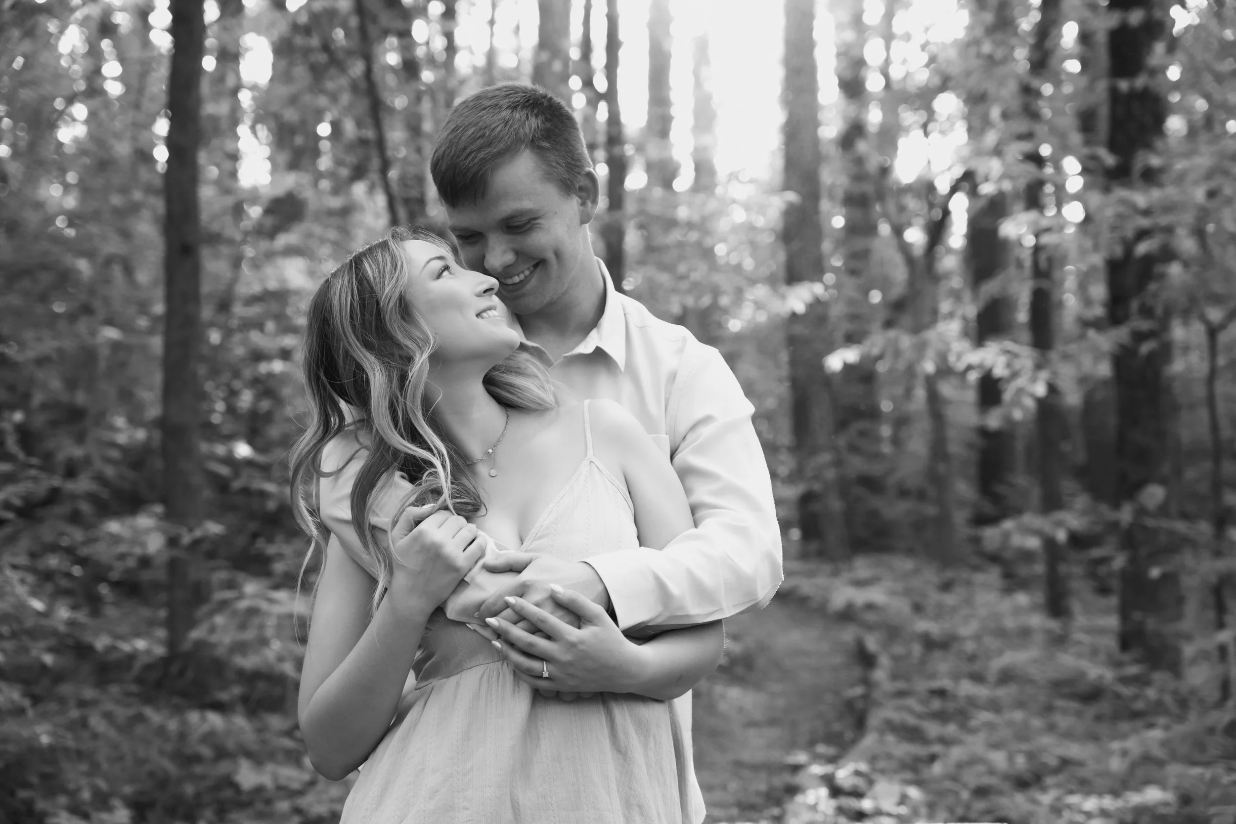 Couple holding hands and looking at each other in wooded area on trail during engagement photo session at Garden of the Gods in Southern Illinois