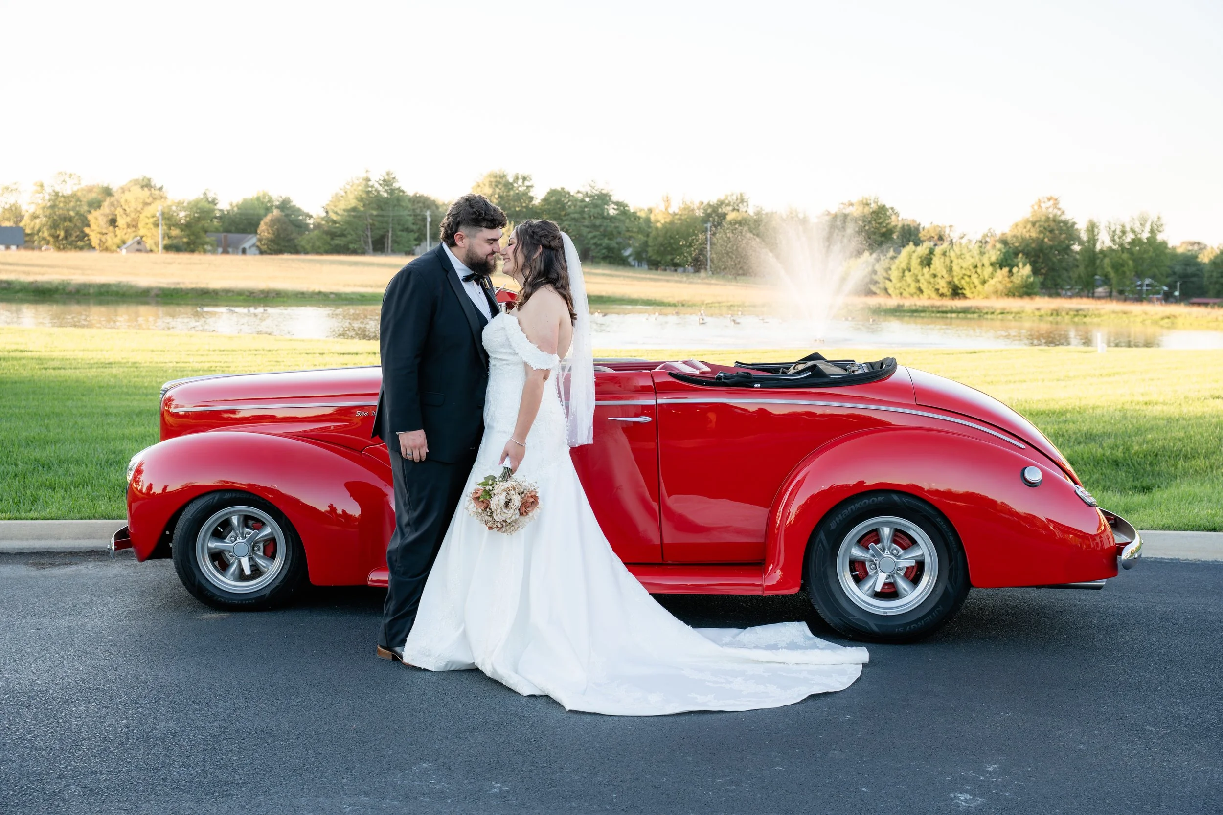 bride and groom photo after wedding ceremony with red classic car at sunset in October at the Commonwealth Event Center wedding venue in Paducah Kentucky