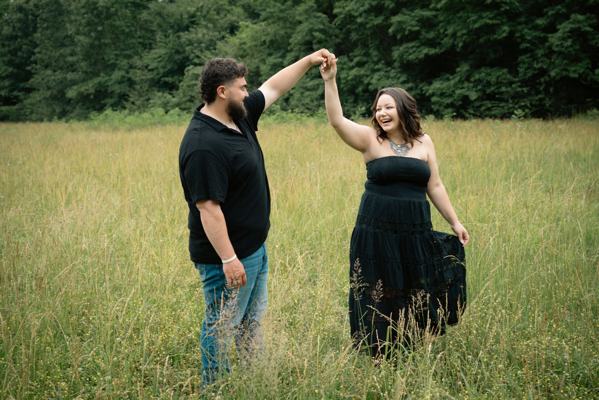 Couple dancing in the field during engagement photo session during summer at Land Between the Lakes, Fenton Campground, Kentucky
