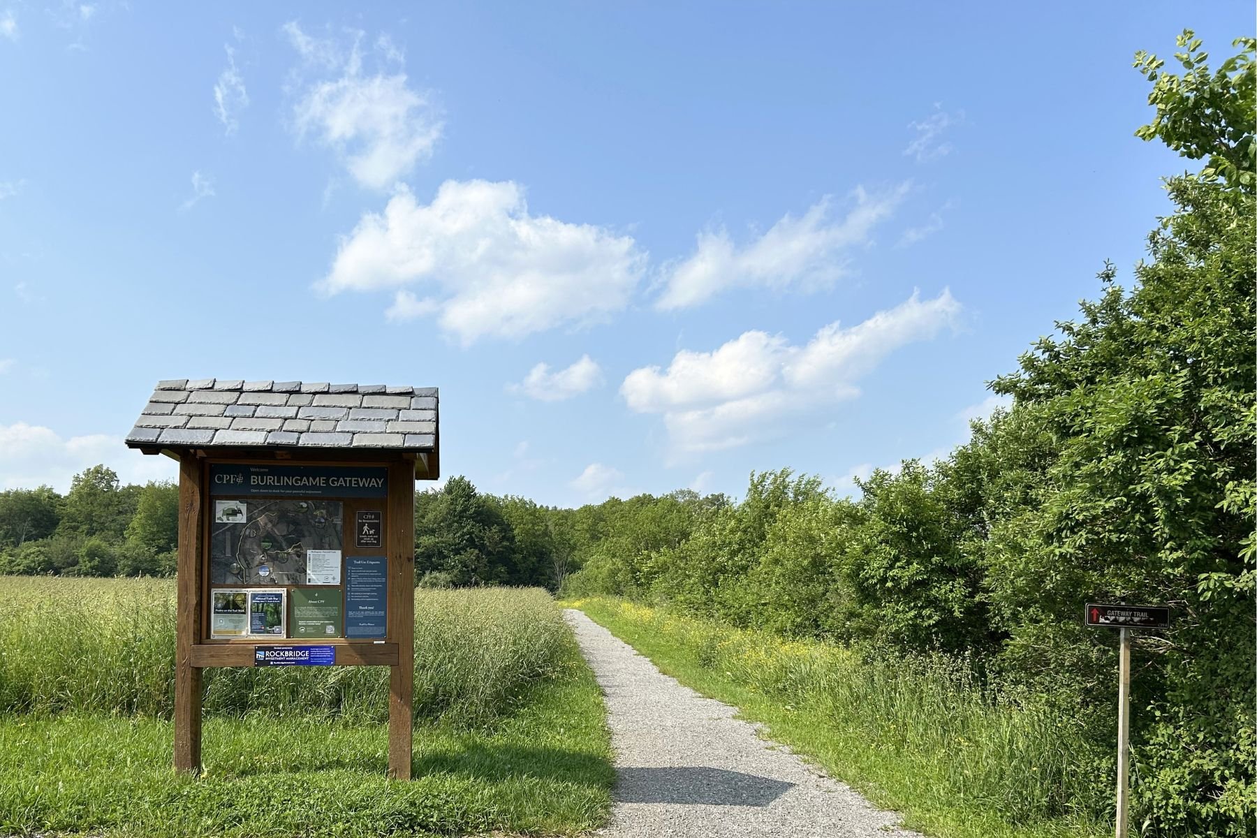 Wooden trail kiosk next to gravel trail