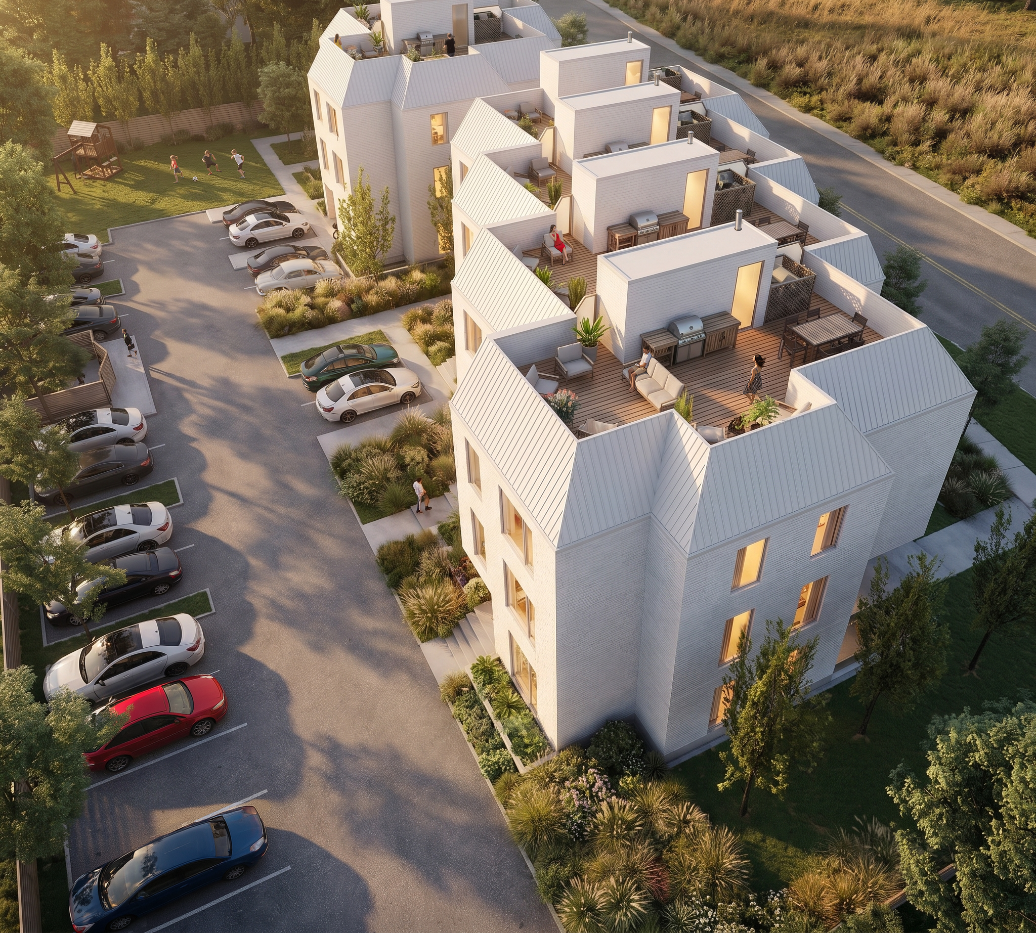 Aerial view of modern white apartment complex with rooftop patios, parking lot with cars, children playing in a grassy yard, and landscaped greenery.