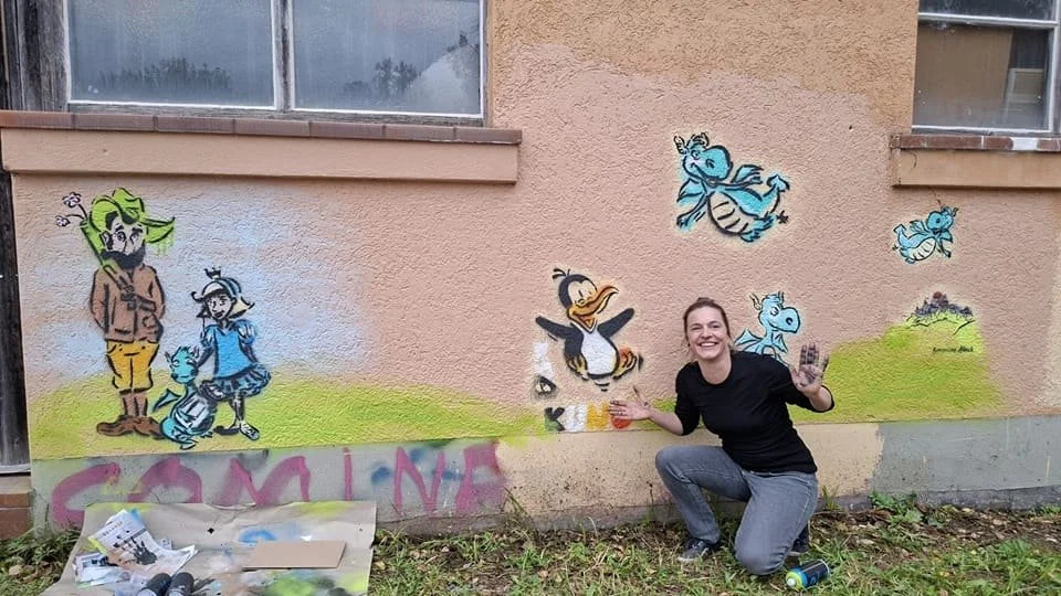 Simone posiert vor der Hallen Fassade mit den gesprühten Kunstwerken darauf