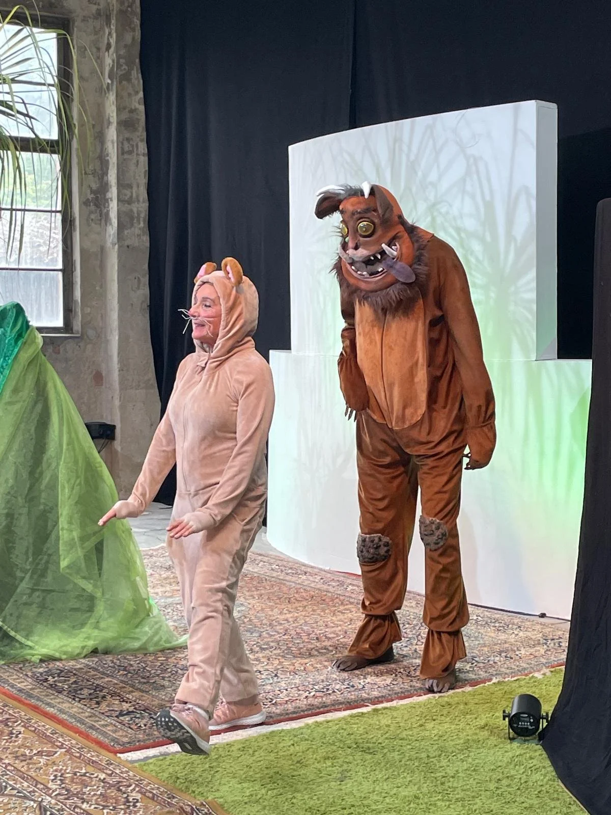 Hinter der Maus, welche gerade beim Laufen ist, steht ein riesiges, braunes, behaartes Wesen, der Grüffelo