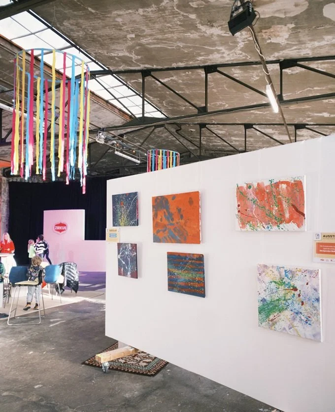 Teil der Ausstellung beim Kinderzirkus am verkaufsoffenen Sonntag. An einer großen Ausstellungswand hängen bunte Bilder auf Leinwand