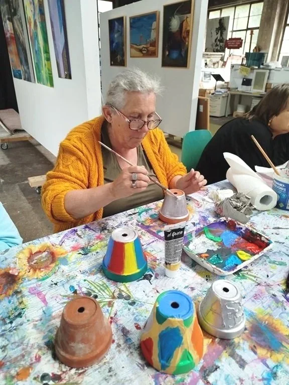 Edel beim Bemalen von Blumentöpfen, alles ist bunt auf dem Tisch