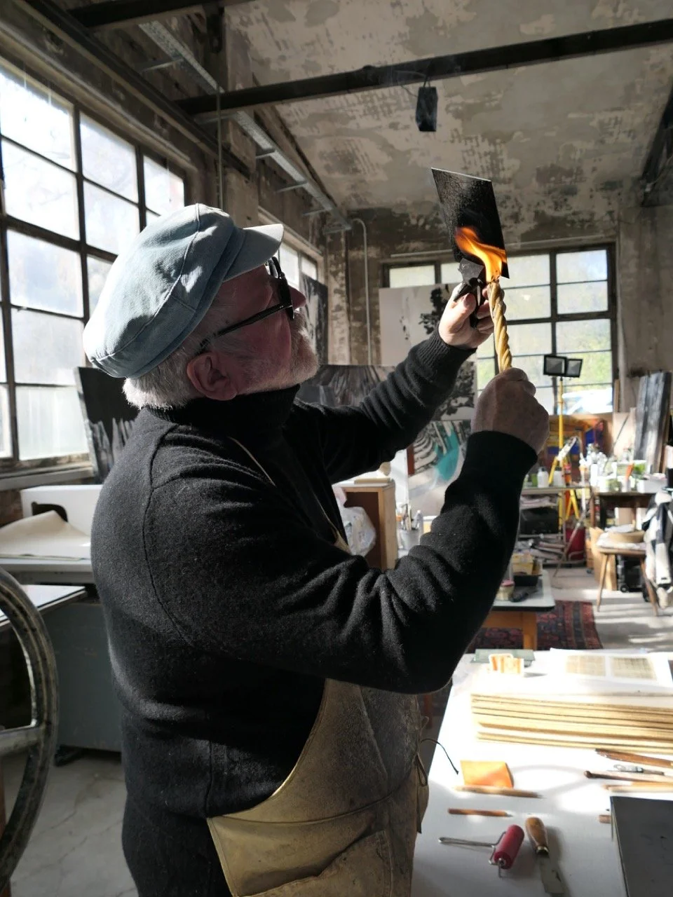 Norbert hält die Platte mit einer Zange und russt sie mit einer Fackel ein