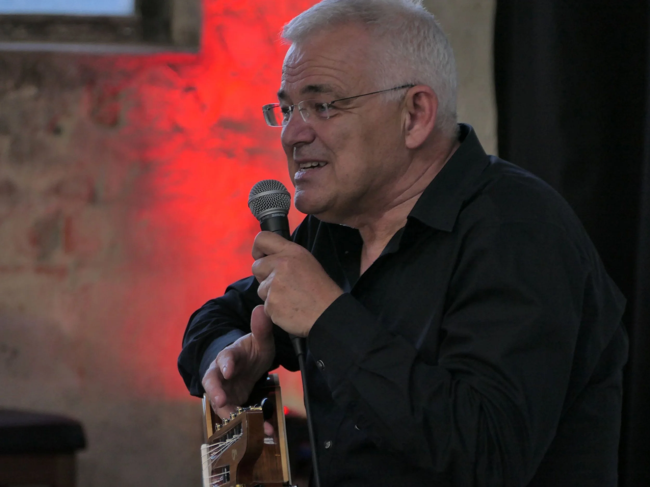 Volker Luft spricht ins Mikro und erzählt die Hintergrundgeschichte eines Songs