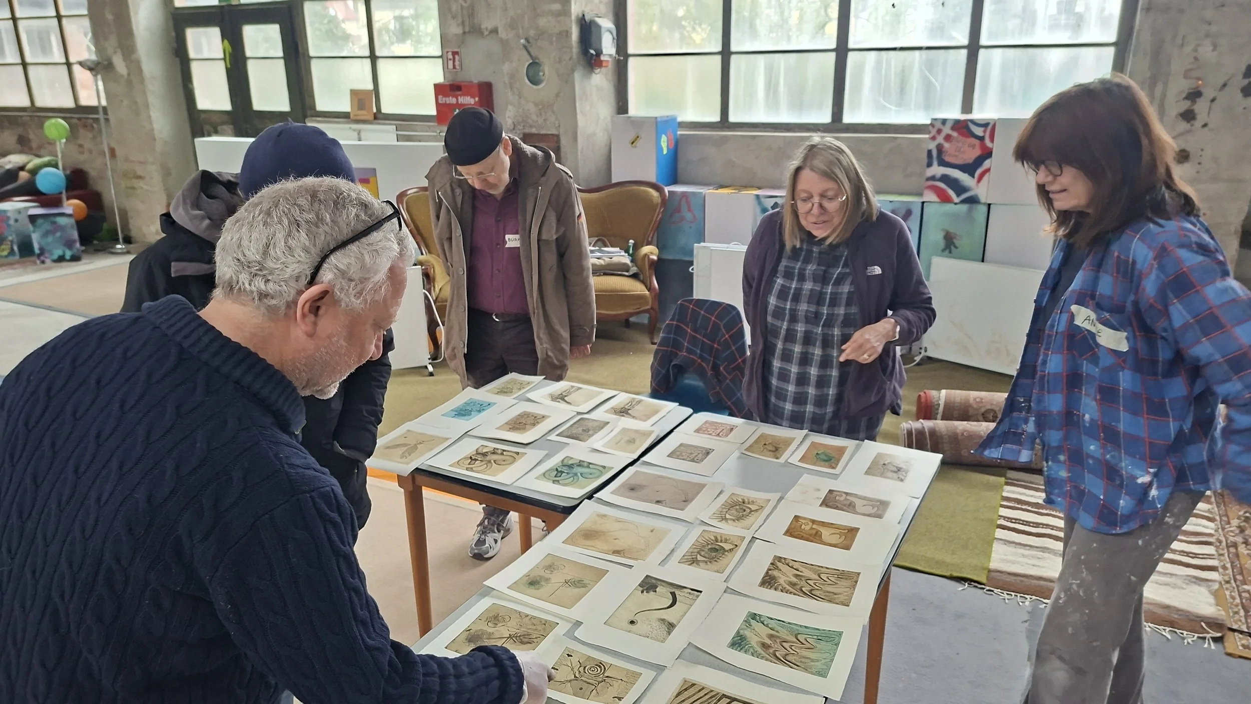 Die Teilnehmer:innen begutachten die verschiedenen Drucke