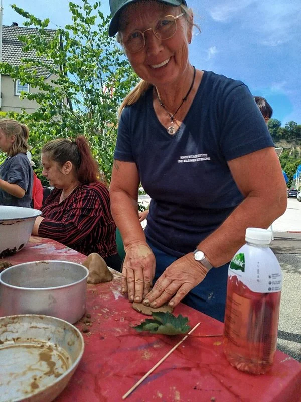 Alex bearbeitet Lehm im Freien bei strahlend blauem Himmel und Sonnenschein