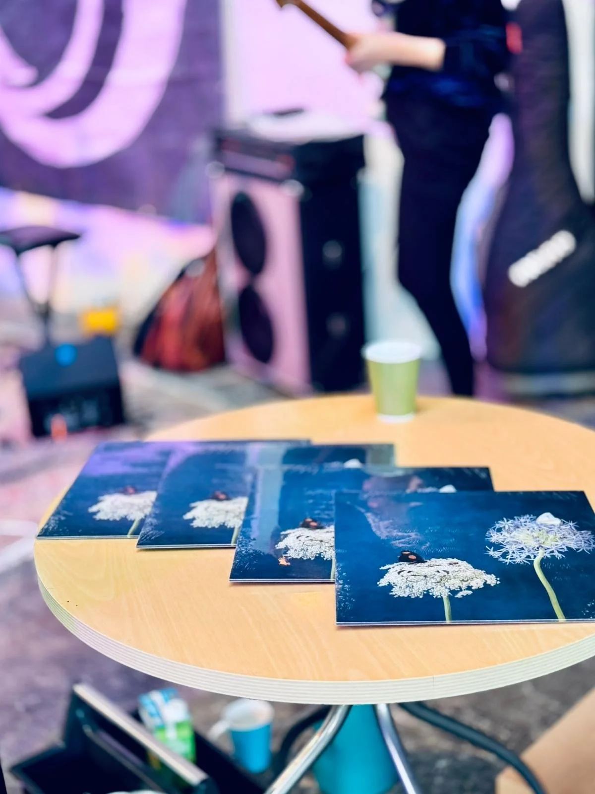 auf einem gelben runden Holztisch liegen blaue Schallplattenhüllen mit zwei weißen Pusteblumen und einem Schmetterling