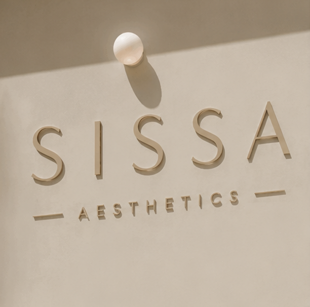 Sign reading "SISSA AESTHETICS" on a wall, illuminated by a ceiling light.