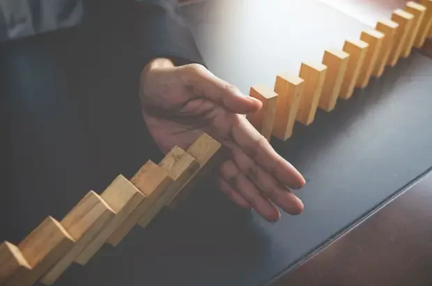 A man stopping a domino effect, highlighting the importance of boundaries - Healing Family Addiction