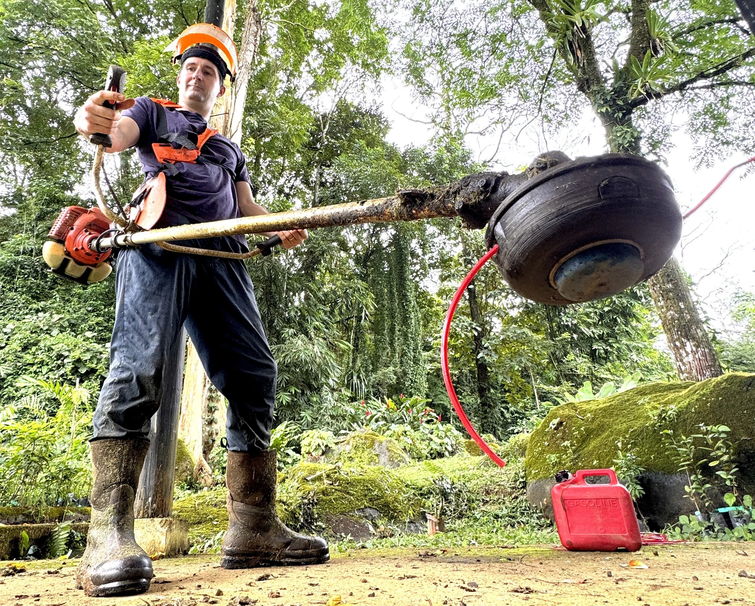 Man is wearing apron and mask, getting ready to weedwack in Costa Rica.