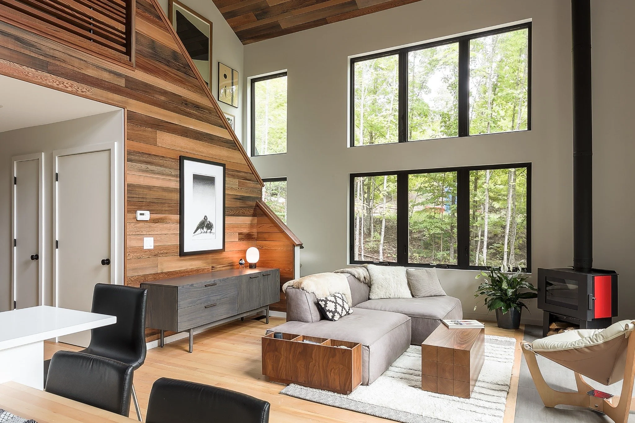 Custom waterfront home design with an open kitchen and living area, white cabinetry, wood-lined ceiling, and loft above.
