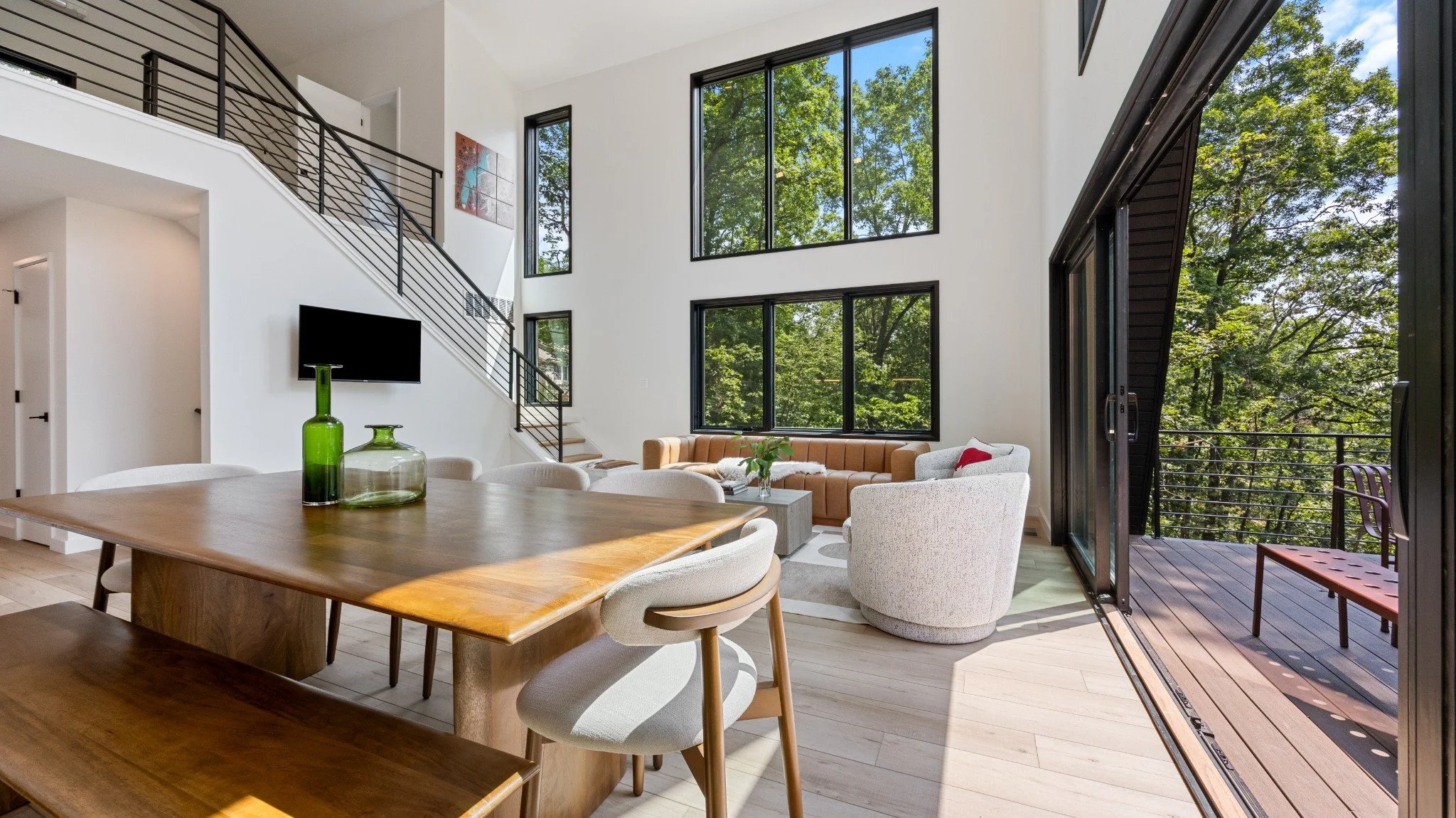 Mountain home designer project featuring a wood dining table, upholstered chairs, black stair railings, and sliding glass doors to a deck.
