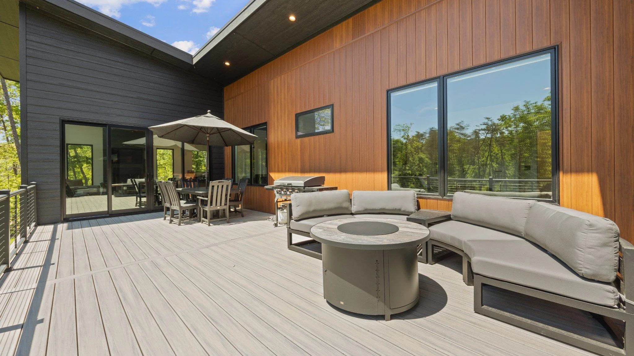  Custom mountain home architect project featuring gray cushioned seating, a round table, an outdoor dining set, and vertical wood siding.