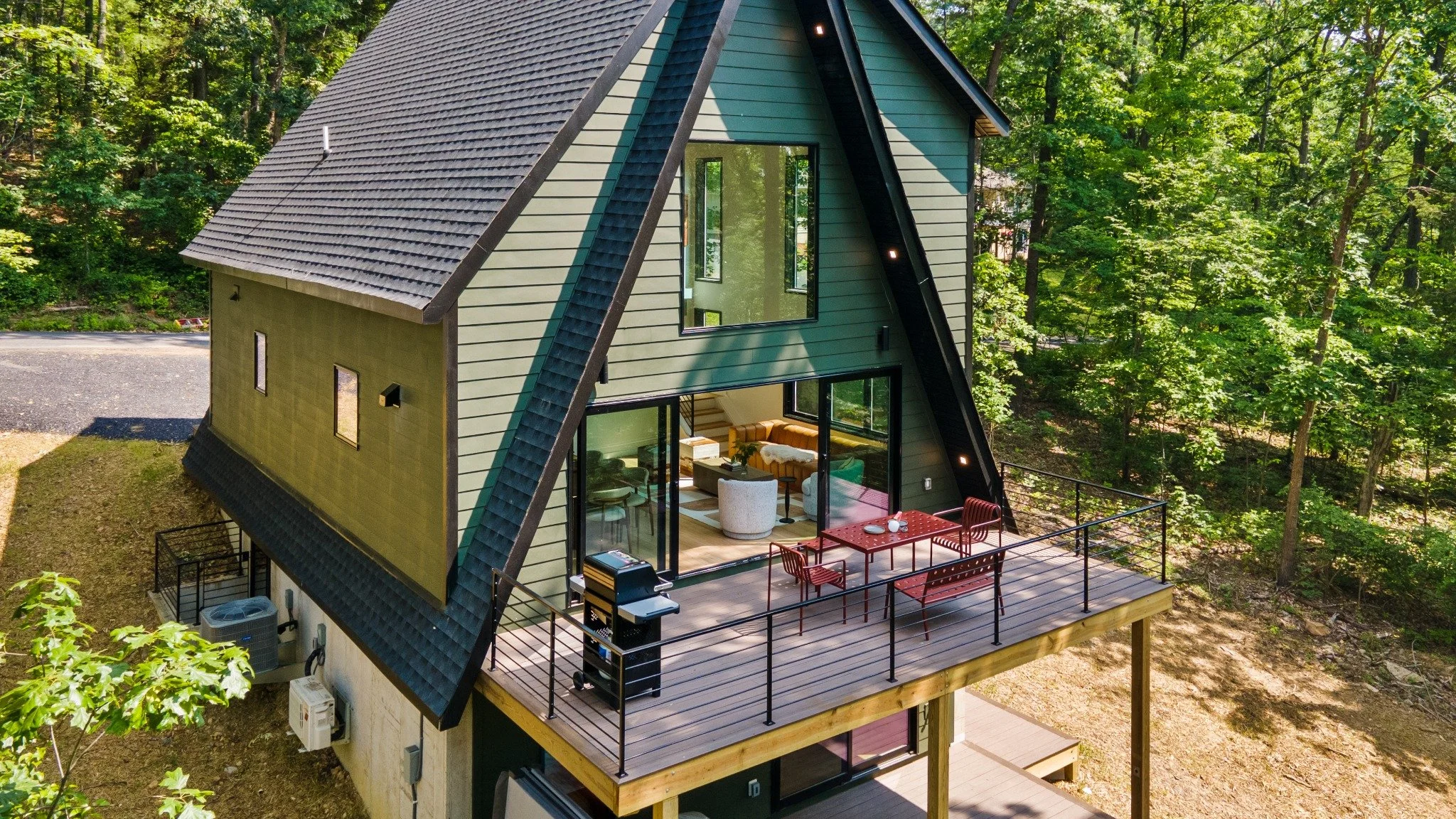  Mountain home architect project featuring an A-frame exterior, large glass doors, and a raised dining deck surrounded by trees.
