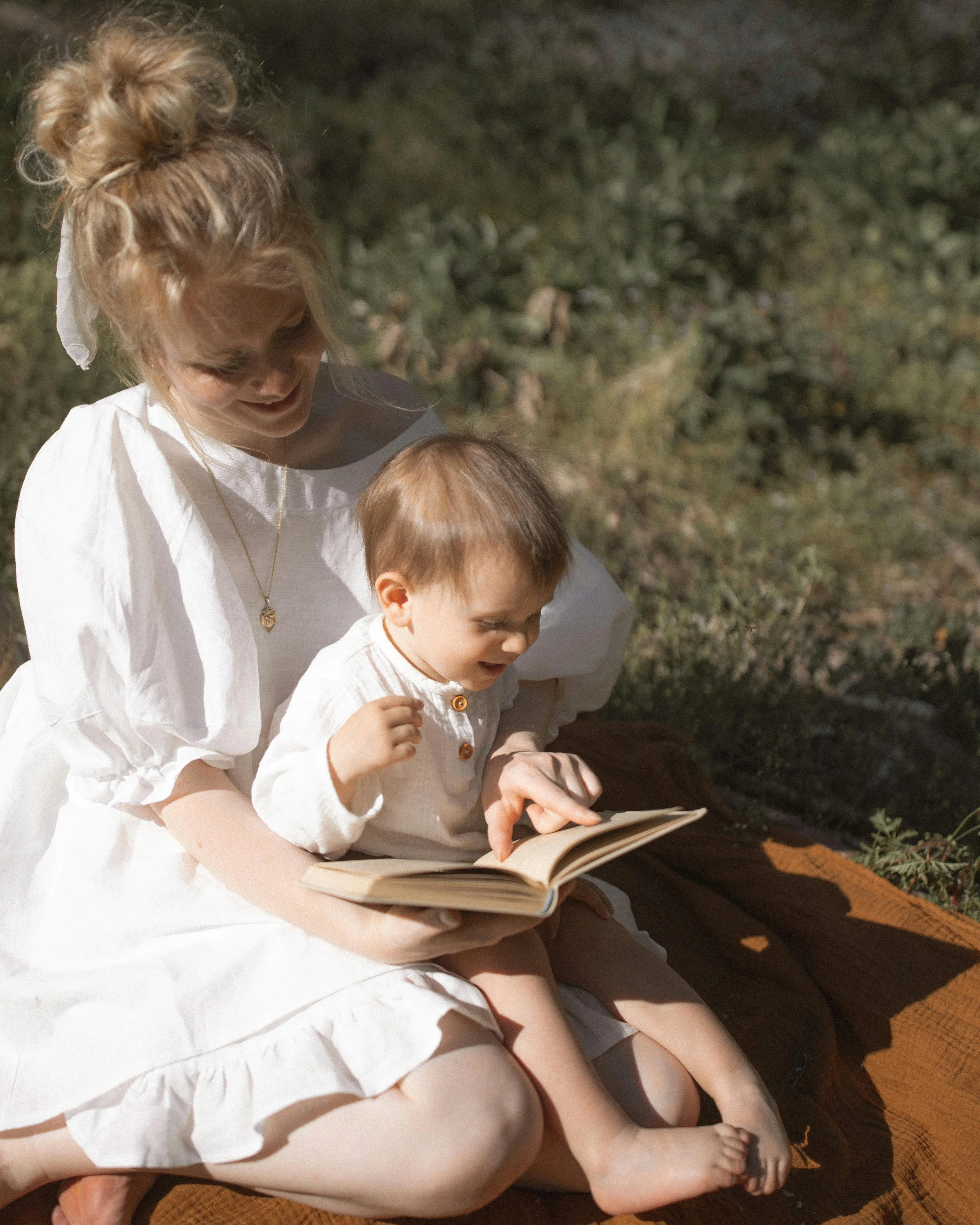 mother and son reading a board book as baby's first summer activities