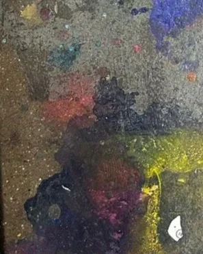 Close-up of a painter's palette with mixed paint colors including blue, purple, pink, green, yellow, and black.