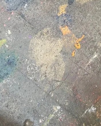 Concrete sidewalk with painted colorful spots and patches.