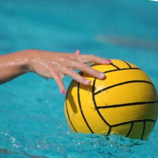 Close-up of a hand grabbing a yellow water polo ball in a swimming pool.