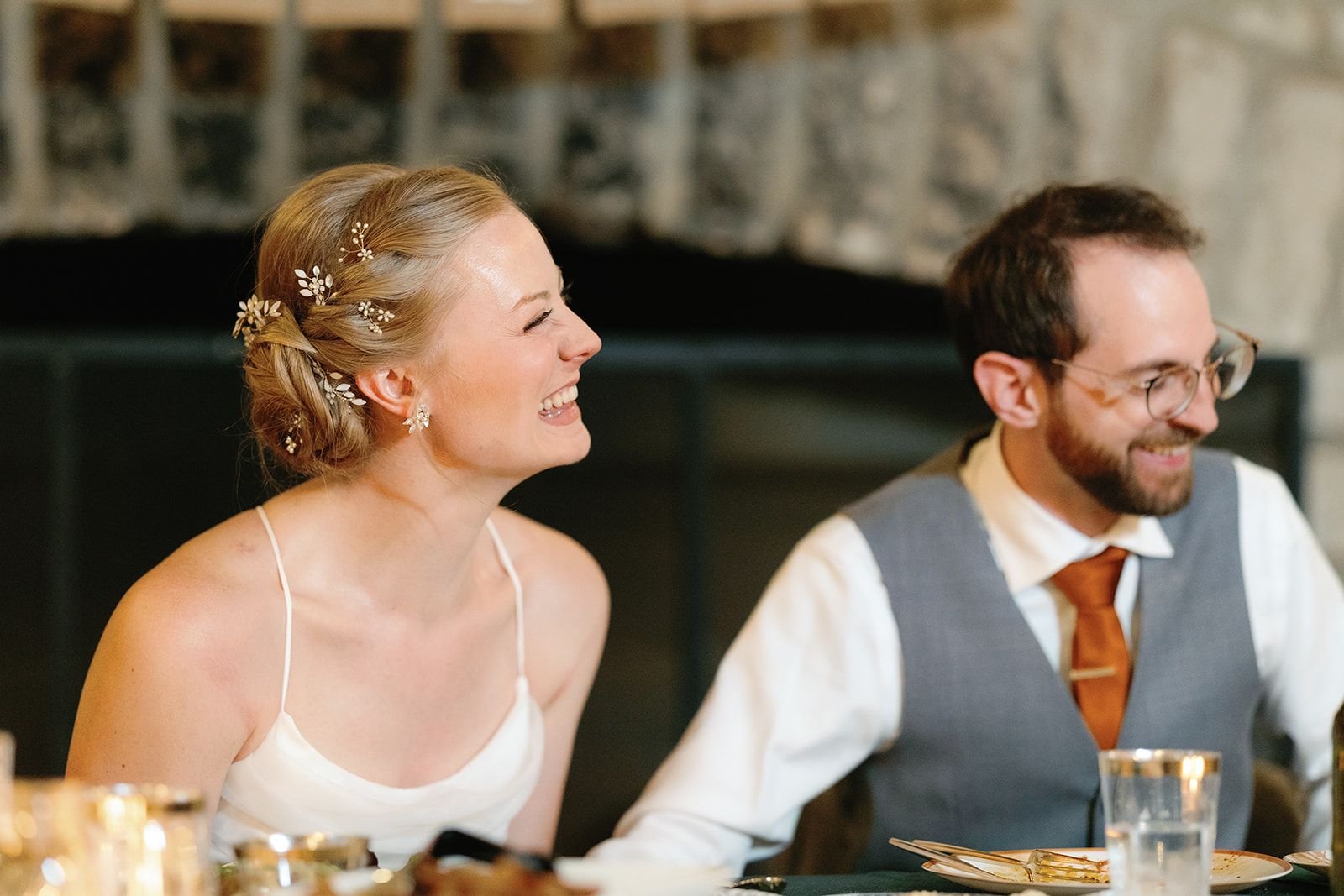 Bride and groom laughing at their table during toasts