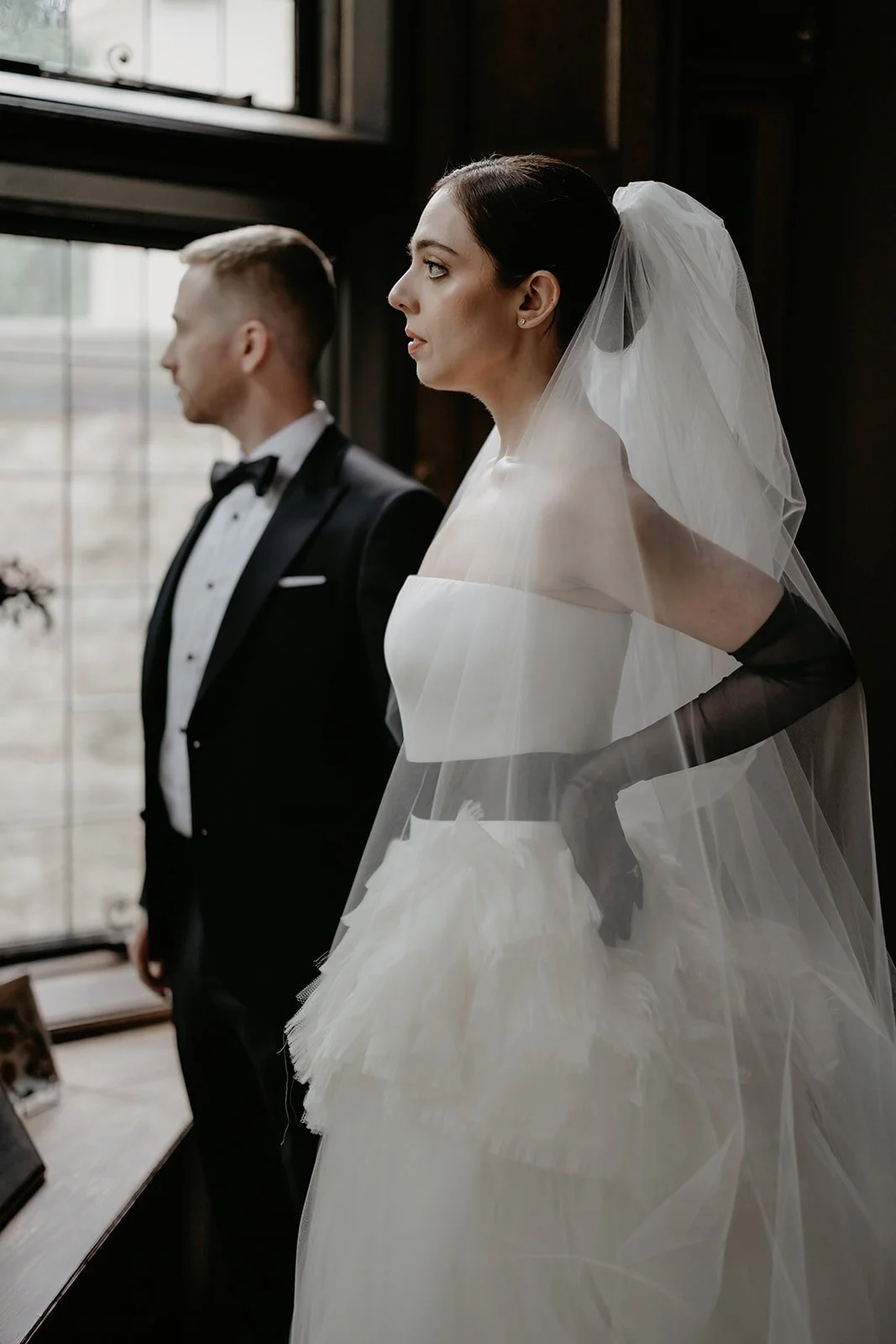 Bride and groom look out a window